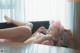 A woman laying on top of a couch next to a window.