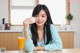 A woman sitting at a table with a cup of orange juice.