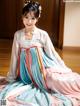 A woman in a blue and pink hanbok sitting on the floor.