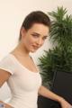 A woman in a white shirt sitting at a desk with a computer.