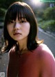 A woman in a pink sweater standing on a train track.