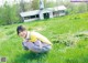 A young woman crouching down in a field of grass.