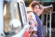 A woman leaning against the side of a white truck.