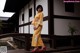 A woman in a yellow kimono standing on a wooden bridge.