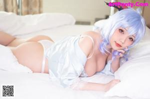 A woman with blue hair laying on a bed.